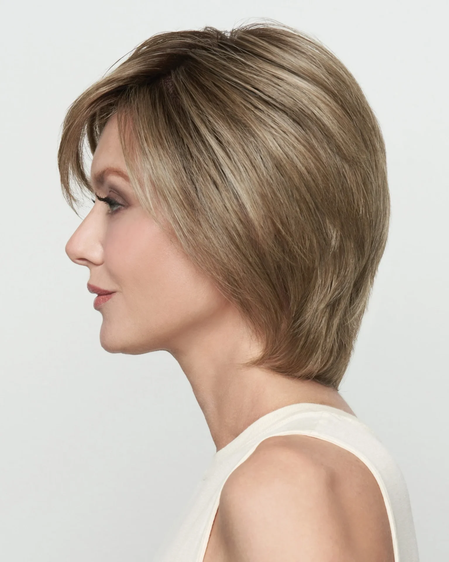 A woman's side view of a layered wig with bangs.